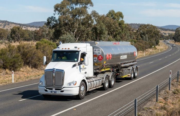 NSW heavy truck carrying dangerous goods on highway displaying Class 3 flammable liquid diamond placards and Emergency Information Panel on side of vehicle